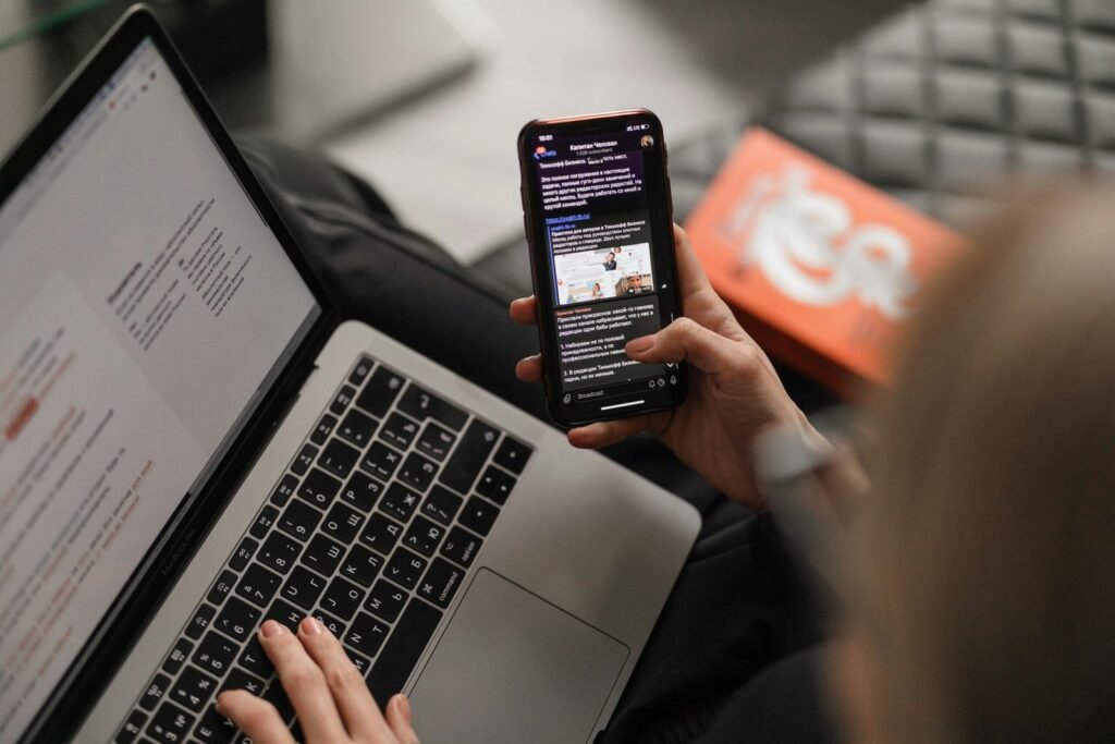 Person using email on a smartphone beside a laptop